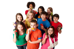 A group of kids hold a fruit or vegetable in their hand and smile.