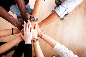A group of people put their hands together in a huddle.