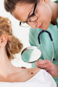 A medical professional looks for moles and melanoma on a patient's back.