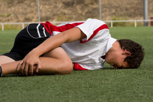 A young athlete gets injured and holds their leg.