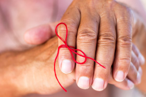 A red ribbon is tied around a person's finger.