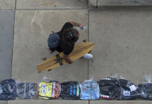 A long boarder shares the Michigan Street sidewalk with a line of backpacks during the attempt to set the Guinness World Record for the world's longest backpack line.