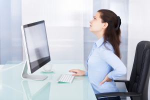 A woman practices good posture at her work desk.