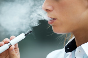 A high schooler smokes an e-cigarette.