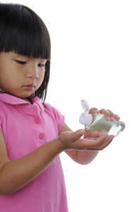 A young girl applies hand sanitizer to her hands.