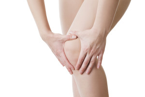 A person holds their knee due to aching joints.