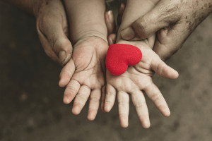 A young boy holds a red, heart-shaped object.
