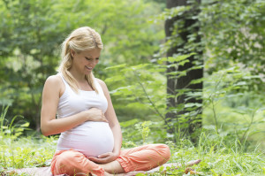 A pregnant woman sits outside.