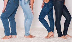 Four women, wearing blue jeans, pose for a photo together.