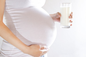 A pregnant woman holds a glass of milk.