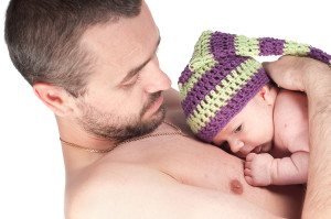A father holds his newborn baby for skin-to-skin contact time.