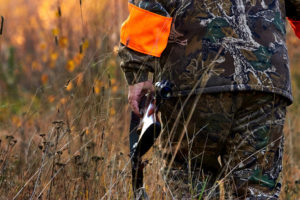 A person wearing hunting gear is shown outside.