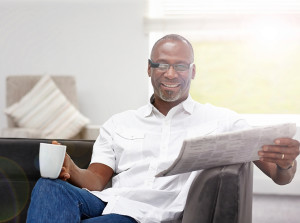 A man reads the newspaper and drinks coffee.
