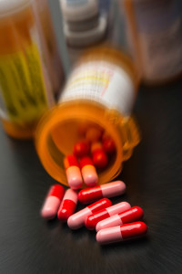 A prescription bottle spills out red-and-pink pills.