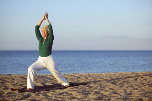 An elderly woman exercises at the beach.