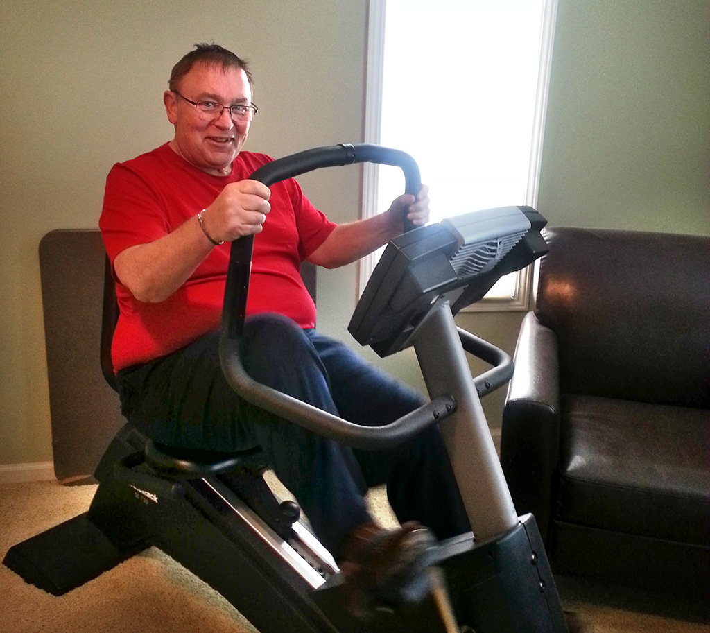 Stephen Schaefer is shown exercising on a stationary bike at home.