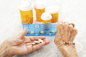 An eldelry adult takes pills out of their weekly pill organizer.
