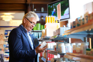 A elderly man looks at nutritional supplements in a store.