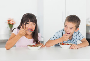 Two kids eat cereal together.