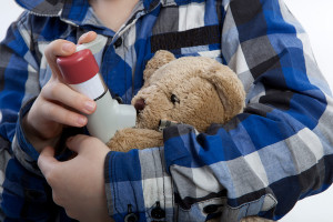 A child gives his teddy bear an asthma inhaler.