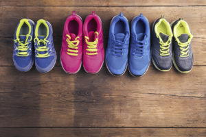 Four pairs of running shoes are shown on a wood floor.