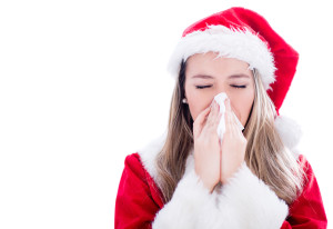 A woman wearing a Santa outfit blows her nose into a tissue.