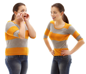 A woman looks at her own reflection in a mirror, and she appears skinnier.