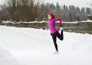 A woman stretches outside in the snow.