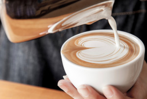 A barista makes a foam-topped latte, complete with lovely latte art.