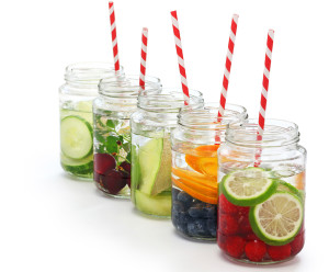 Five jars with infused water is in focus. Each jar contains different ingredients.