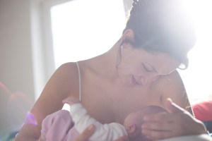 A woman holds her baby and breastfeeds.
