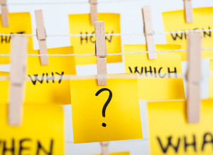 A sticky note is shown with a question mark on it. Other sticky notes are next to it and say, "why," "which," "how, "when," and "what."