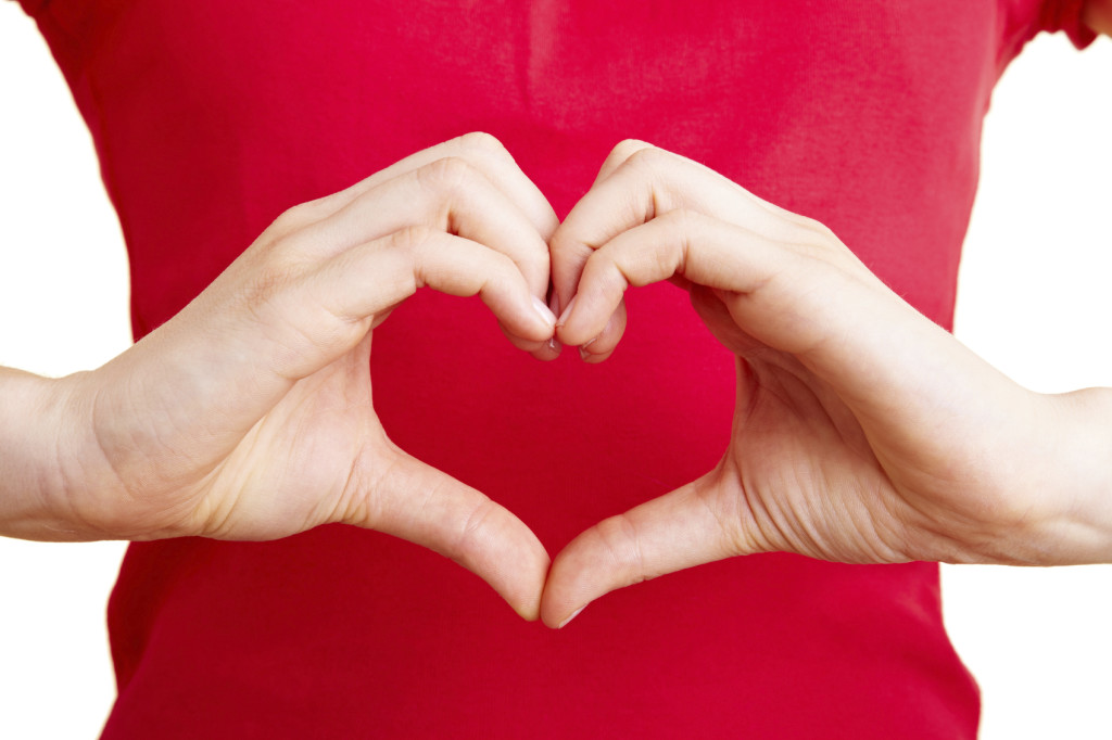 A woman holds her hands together to form a heart.