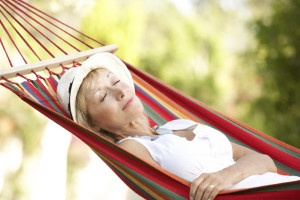 A woman appears asleep as she lies in a hammock.