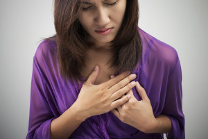 A woman places her hands over her heart and appears uncomfortable.