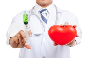 A medical professional holds a vaccine in one hand and a heart-shaped object in the other.