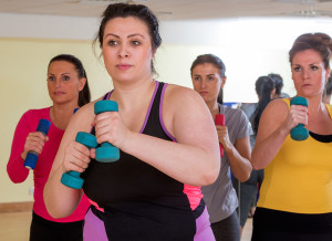 A group of women workout together by exercising with dumbbells.