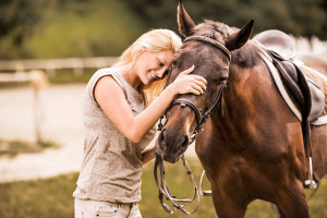 A woman hugs a horse and smiles.