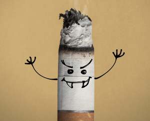 A cigarette is shown with an evil-looking face drawn on it.