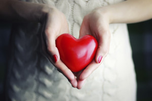 A woman holds a red, heart-shaped object in her hands.