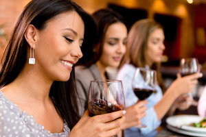 A group of woman drink a glass of red wine with dinner.
