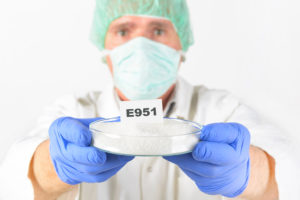 A medical professional holds a dish with a piece of paper that reads, "E951."