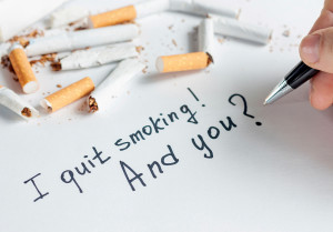 A person writes, "I quit smoking! And you?" on a piece of paper.