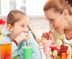 A mother drinks a smoothie through a straw with her daughter.