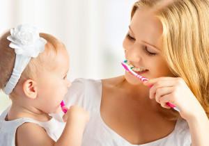 A mother brushes her teeth with her daughter.