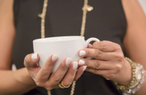 A woman holds a cup of coffee.