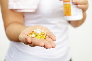 A woman holds out her hand. Her hand is filled with dietary supplements.