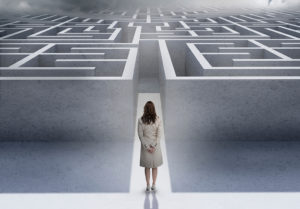 A woman stands outside a labyrinth.