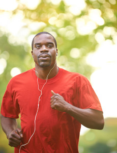 A man runs outside and wears headphones.