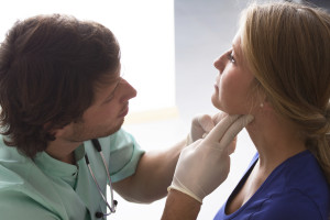 GP examining young woman, who has problems with throat